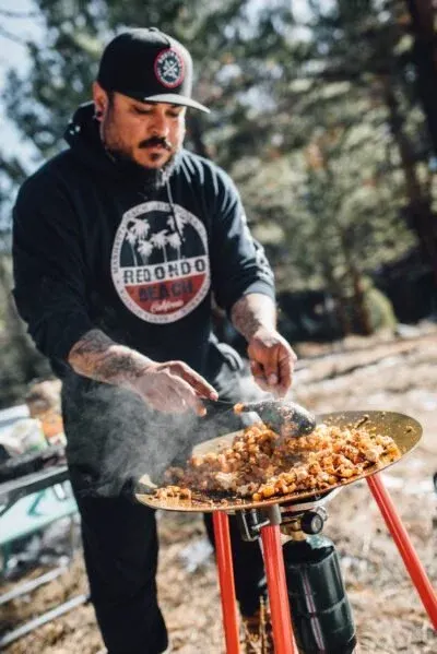 One of the overlanders cooking breakfast on a skottle at camp