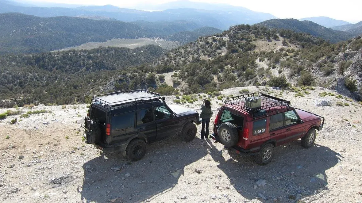Two Land Rover Discovery IIs parked on a mountain overlook
