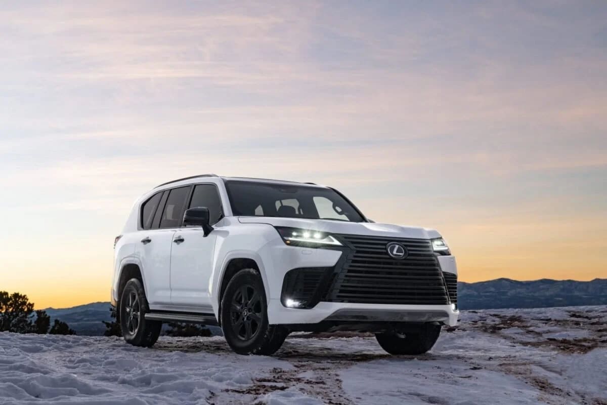 White Lexus LX 600 parked on a snowy ridge at sunset