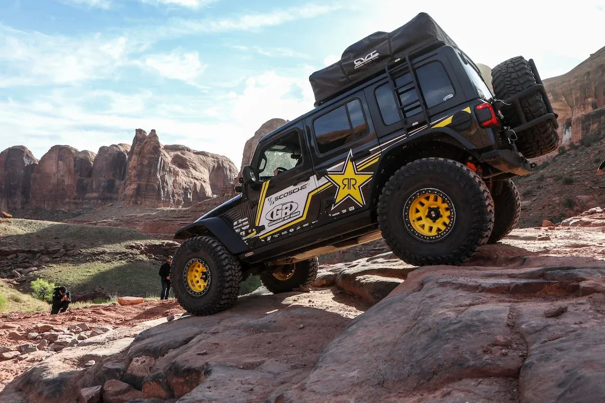 Black Jeep Wrangler JL tilted on a rock ledge
