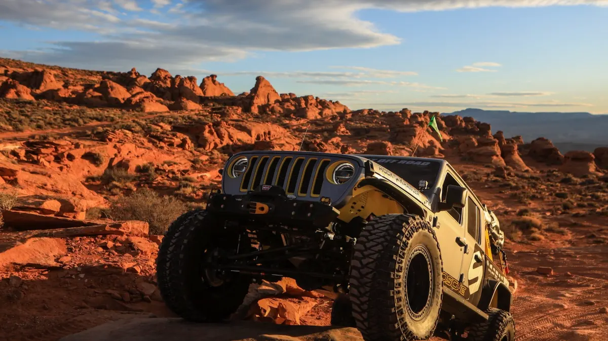 Jeep Gladiator parked among red rock formations at sunset