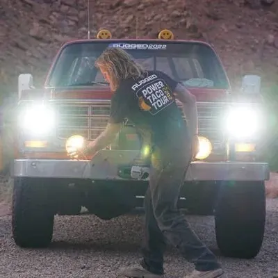 Woman adjusting KC HiLites lights on a red pickup at night