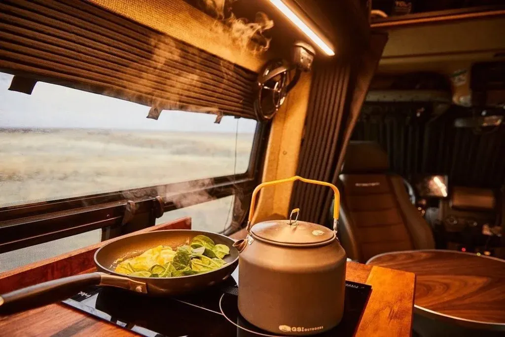Kettle and pan on a stove inside a camper van at sunset