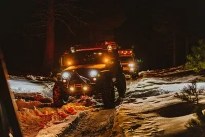 Jeep Wrangler in the snow at night with lights on