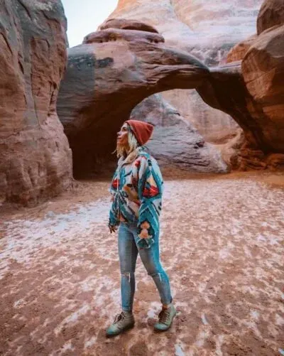 Woman standing under a red rock arch