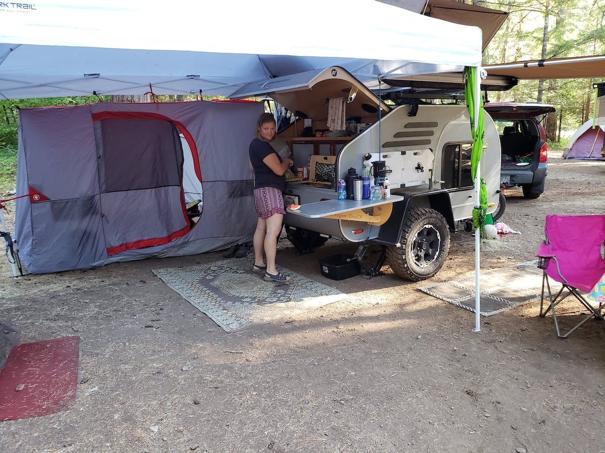 Teardrop camper set up at a campsite with a canopy