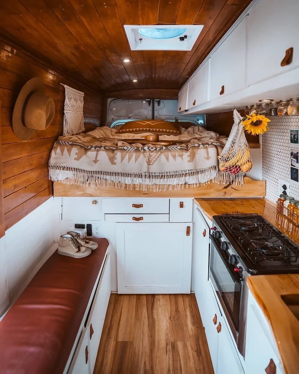 Interior of a camper van with bed, kitchen and wood floor