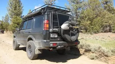 Land Rover Discovery II with rear ladder and spare tire on a dirt road