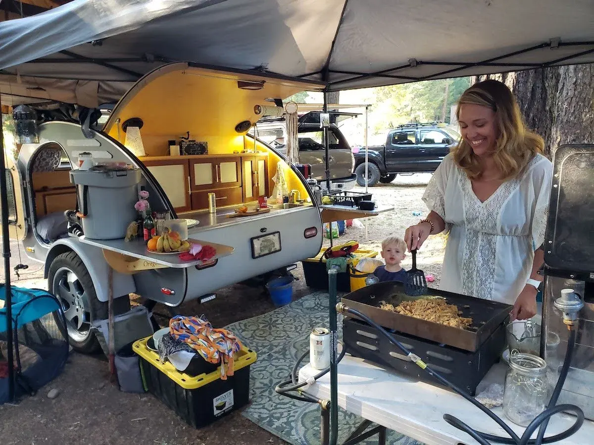Woman cooking at the galley of a teardrop trailer