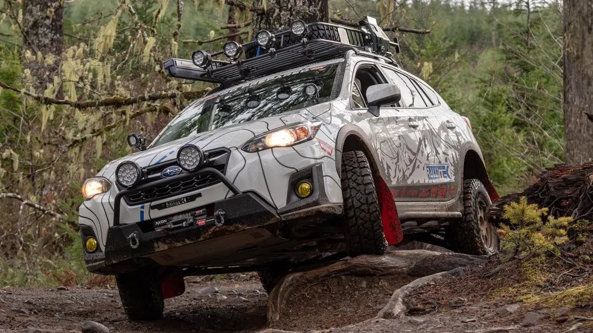 Subaru Crosstrek with roof rack and lights on a forest trail
