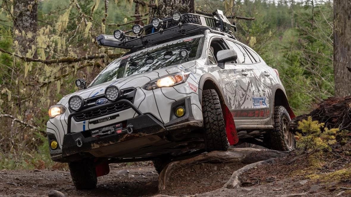 Subaru Crosstrek with roof rack and lights on a forest trail